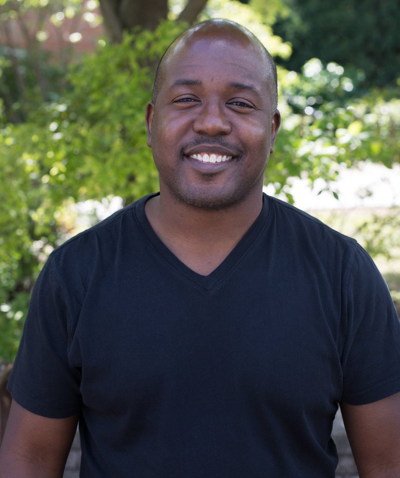 man in black t-shirt in front of trees