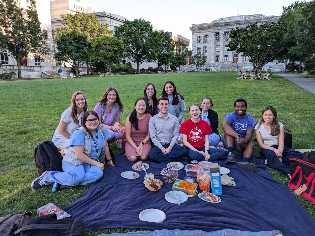 Group photo: members of HER Team 2024–2025 (eleven individuals) at a picnic on the Harvard Medical School campus