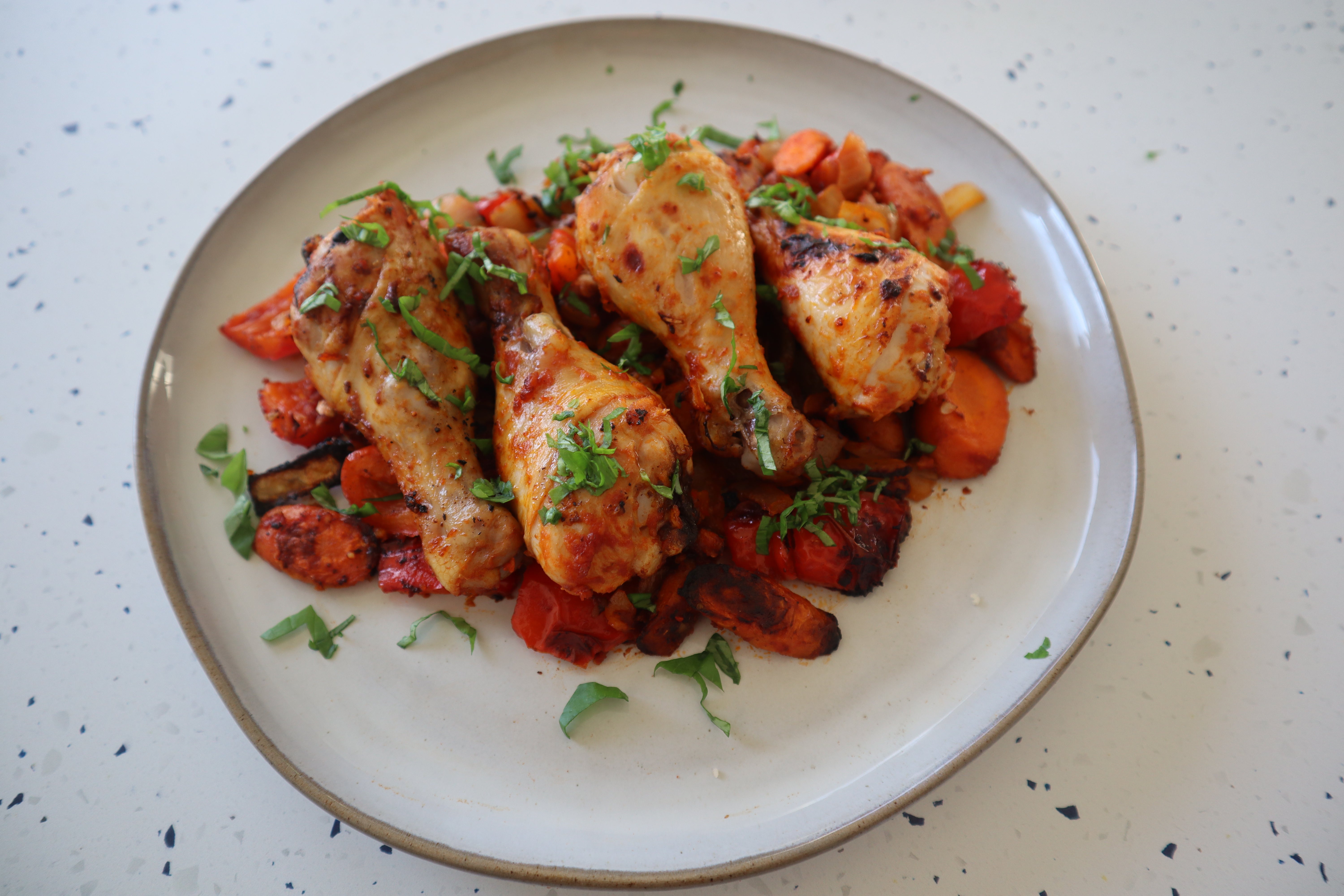 Harissa roasted chicken (drumsticks) on top of roasted carrots and peppers