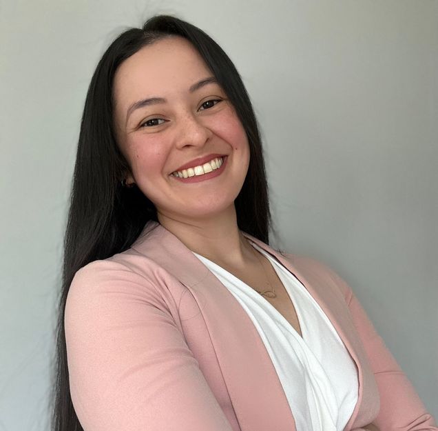 woman with arms crossed wearing pink blazer and white shirt