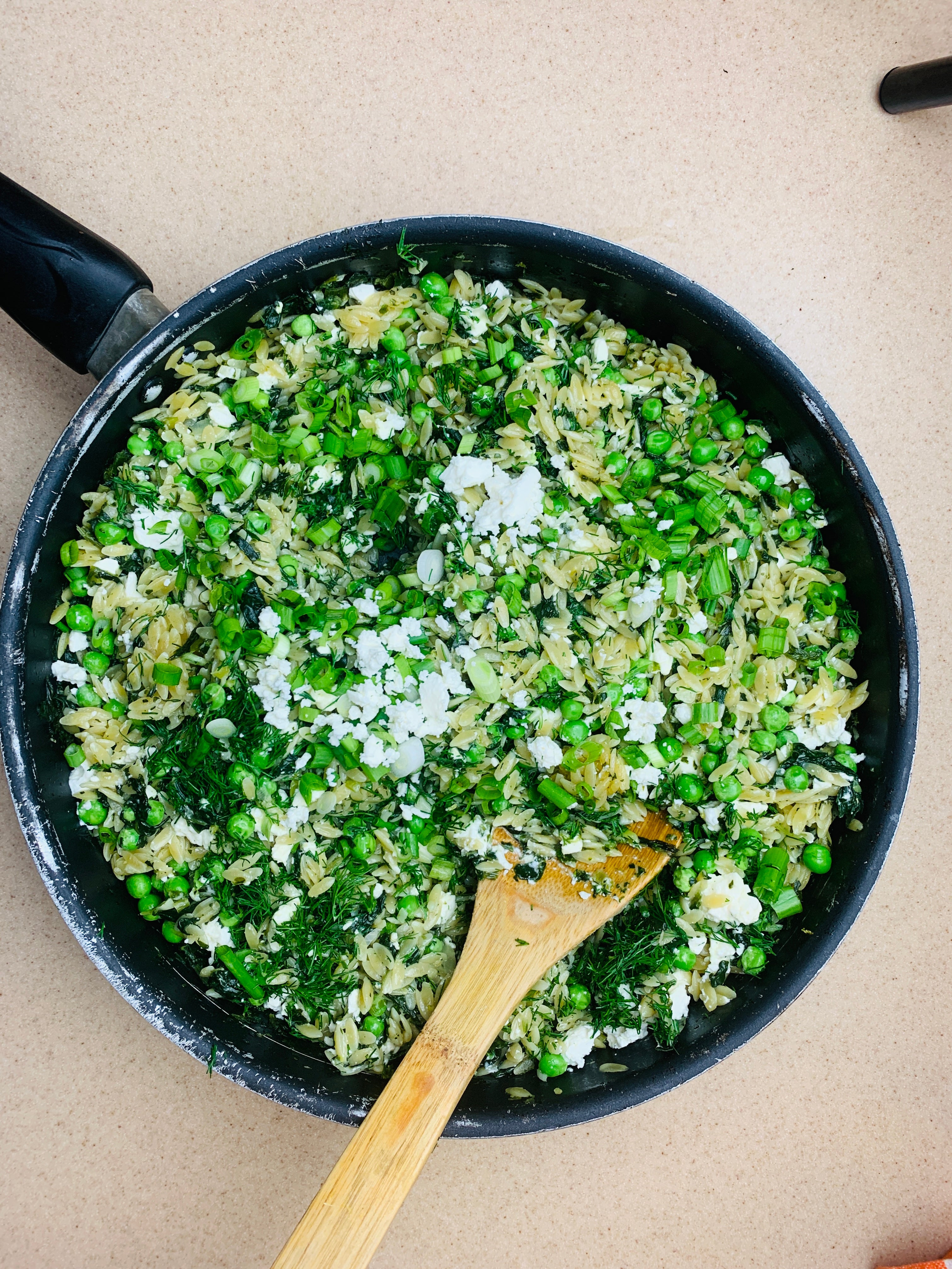 Orzo en una sartén con espinacas y queso feta servido