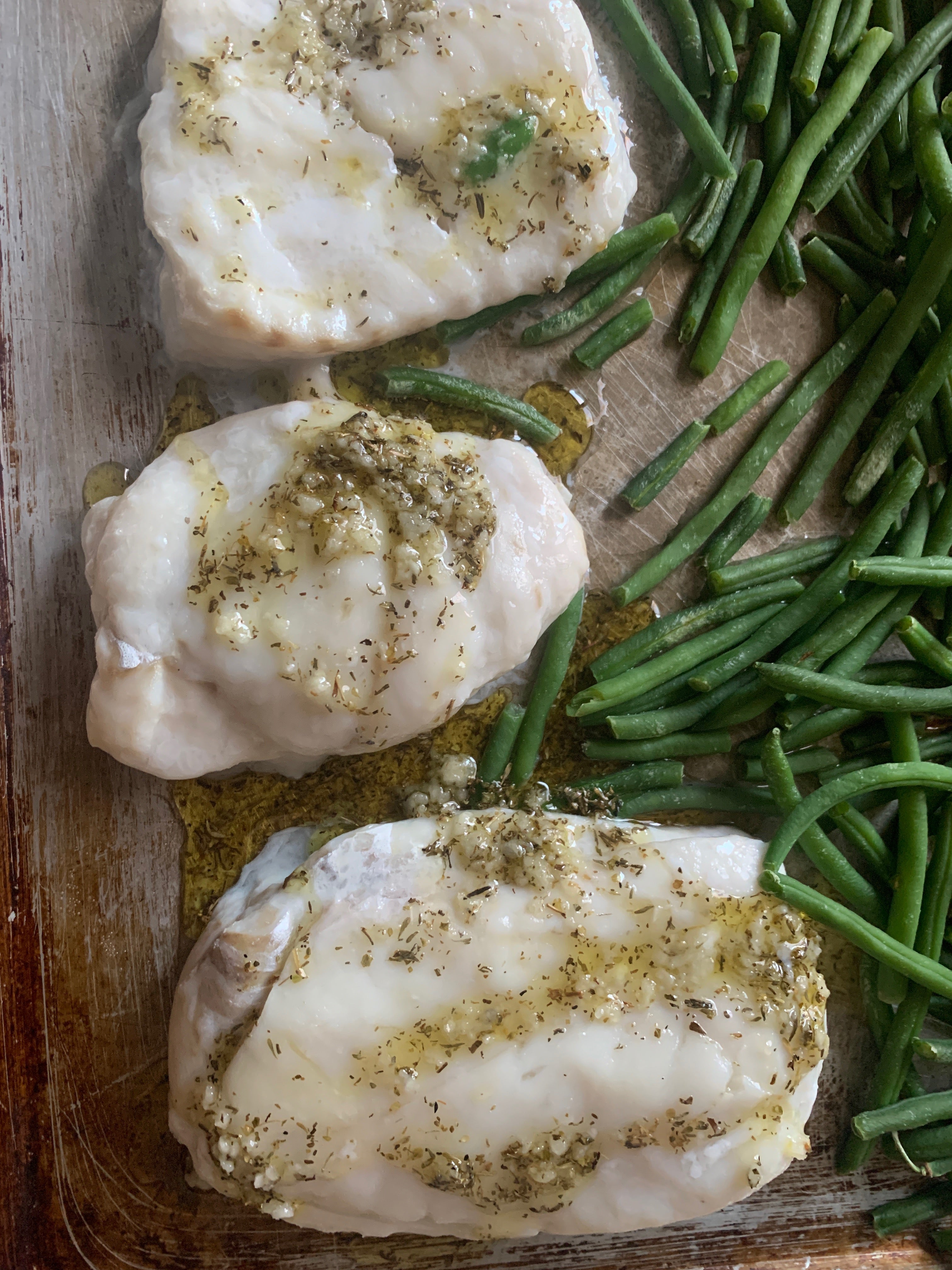 3 filets of haddock topped with lemon garlic sauce, with greens beans on the side. All on a sheet pan. 