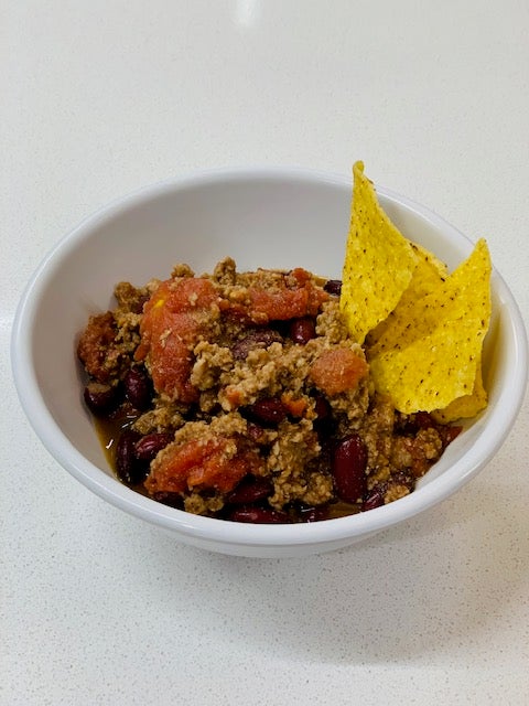 Chili served with tortilla chips on top. 