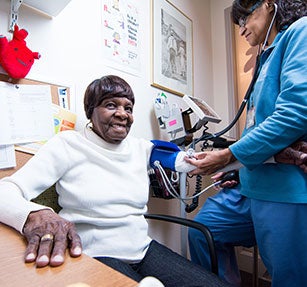 Primary care physician is taking a geriatric patient's vitals.