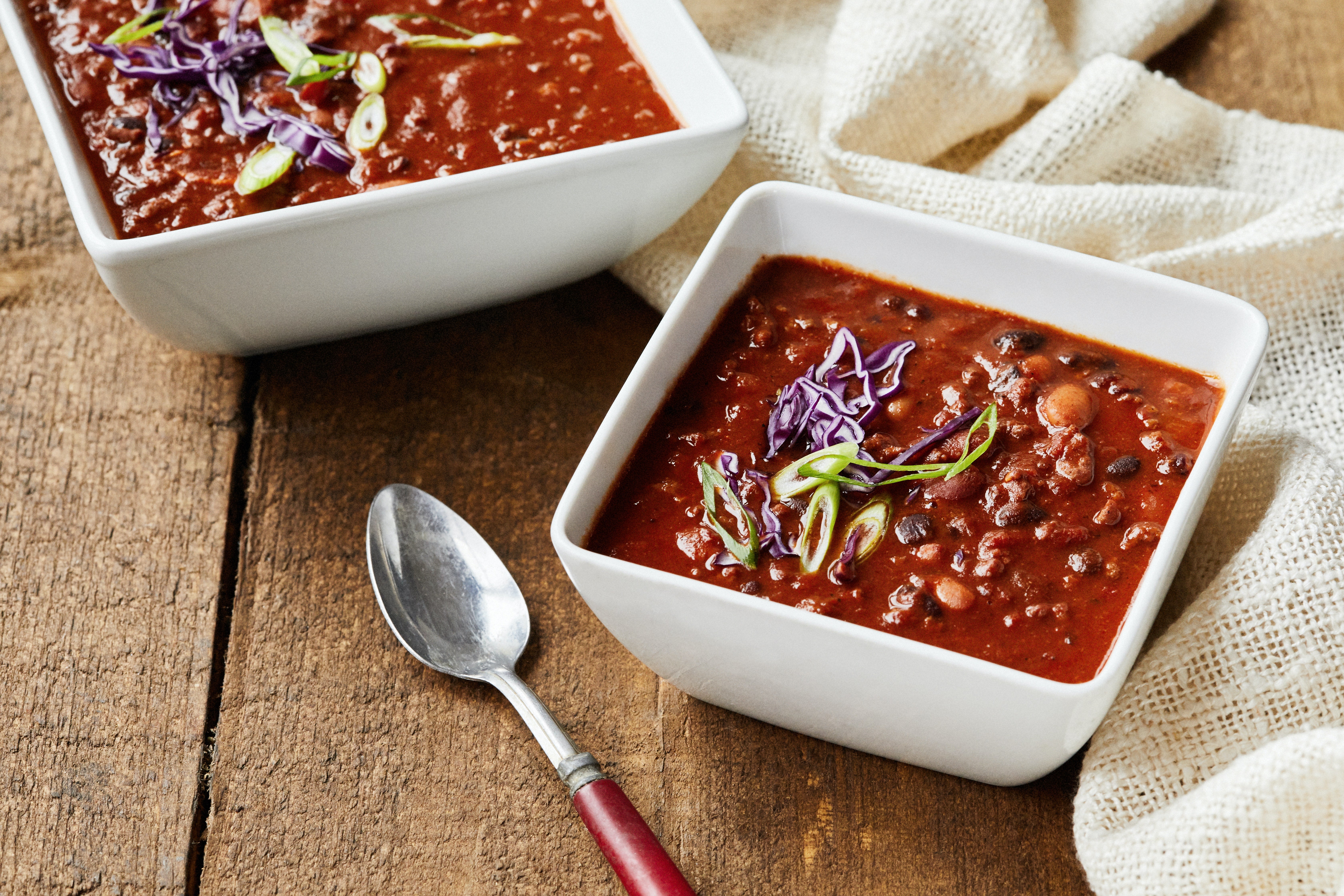dos tazones de chili con frijoles cubiertos con hierbas y repollo