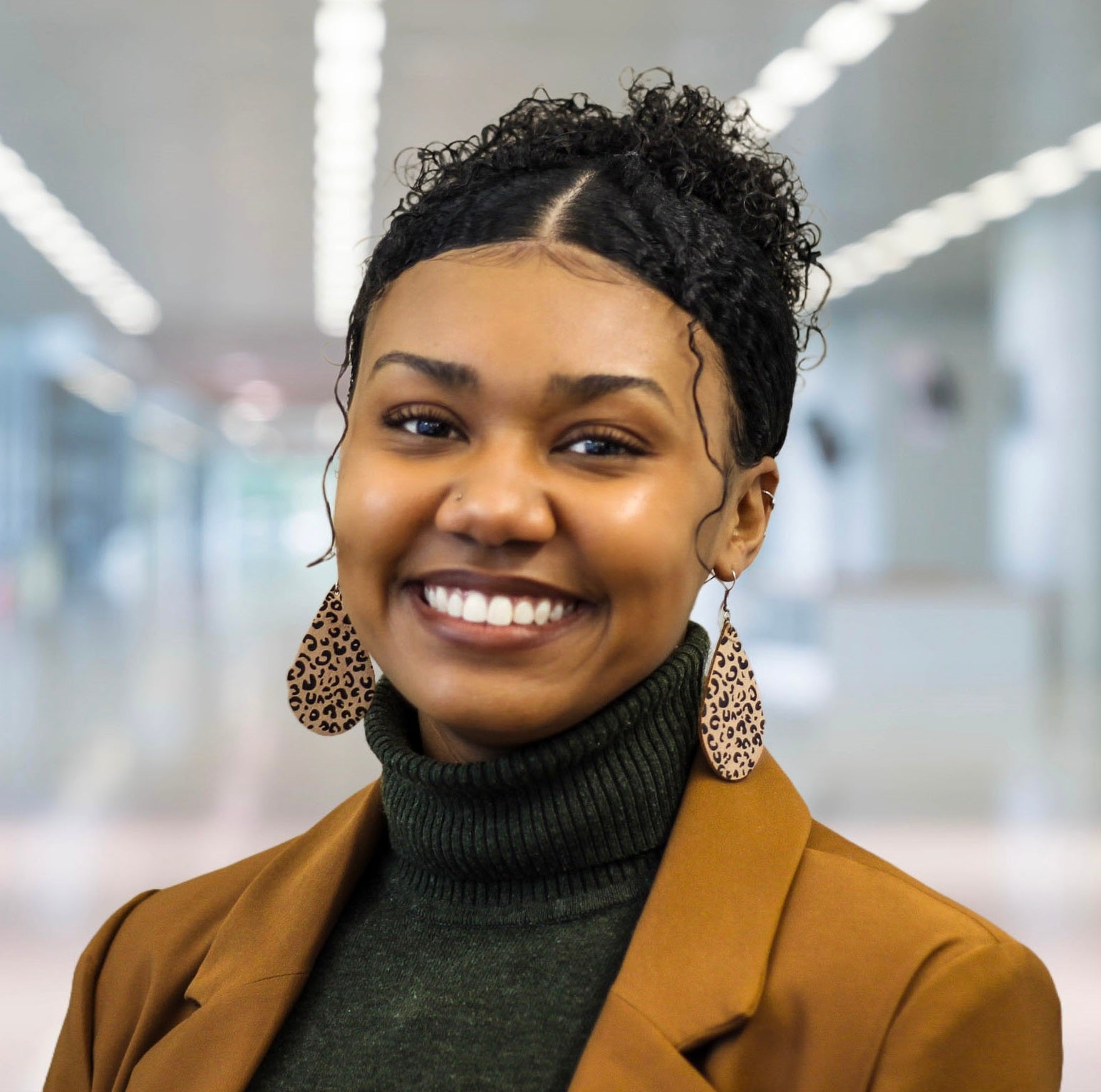 woman in brown blazer and black shirt with big earrings