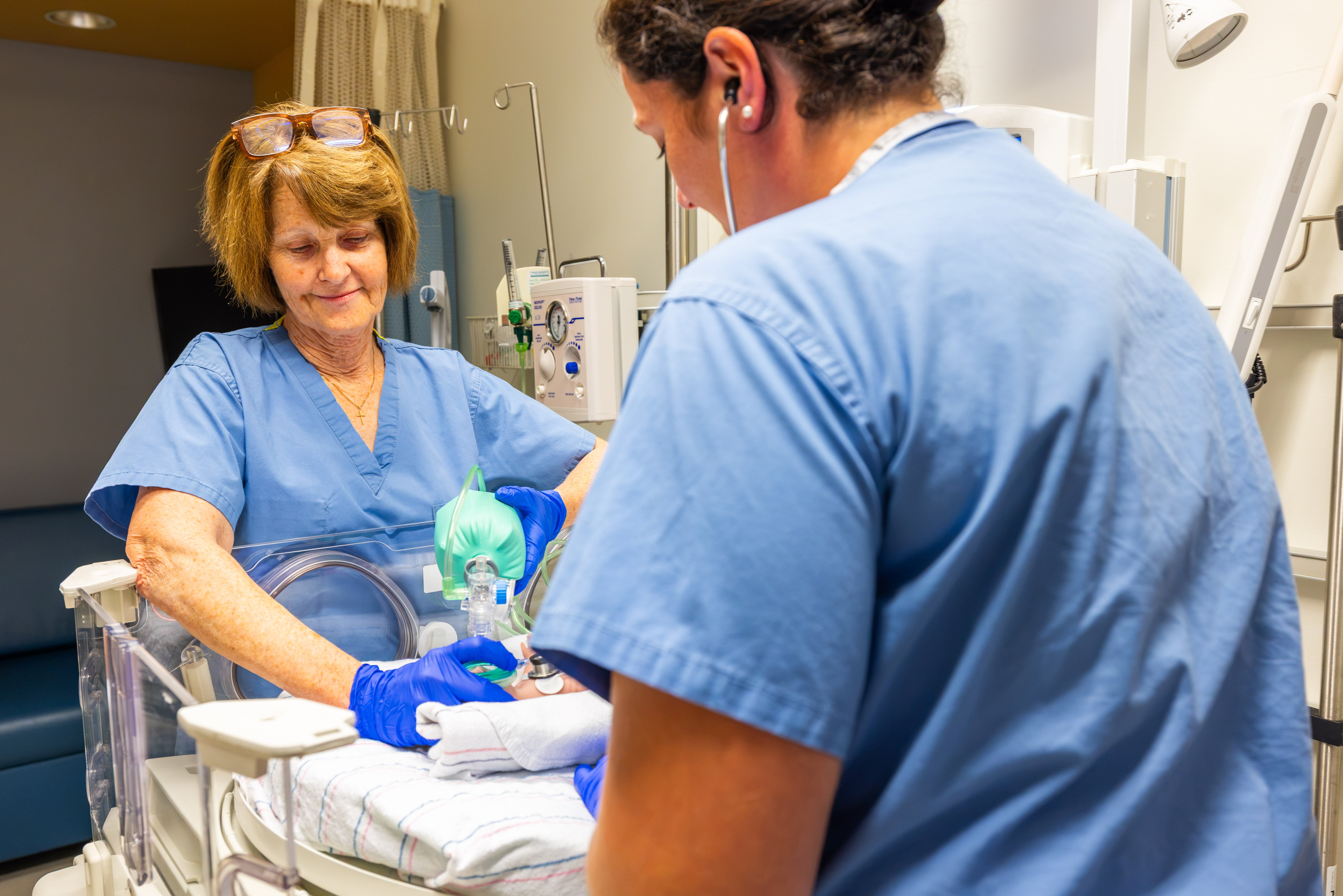 Two staff peering over baby