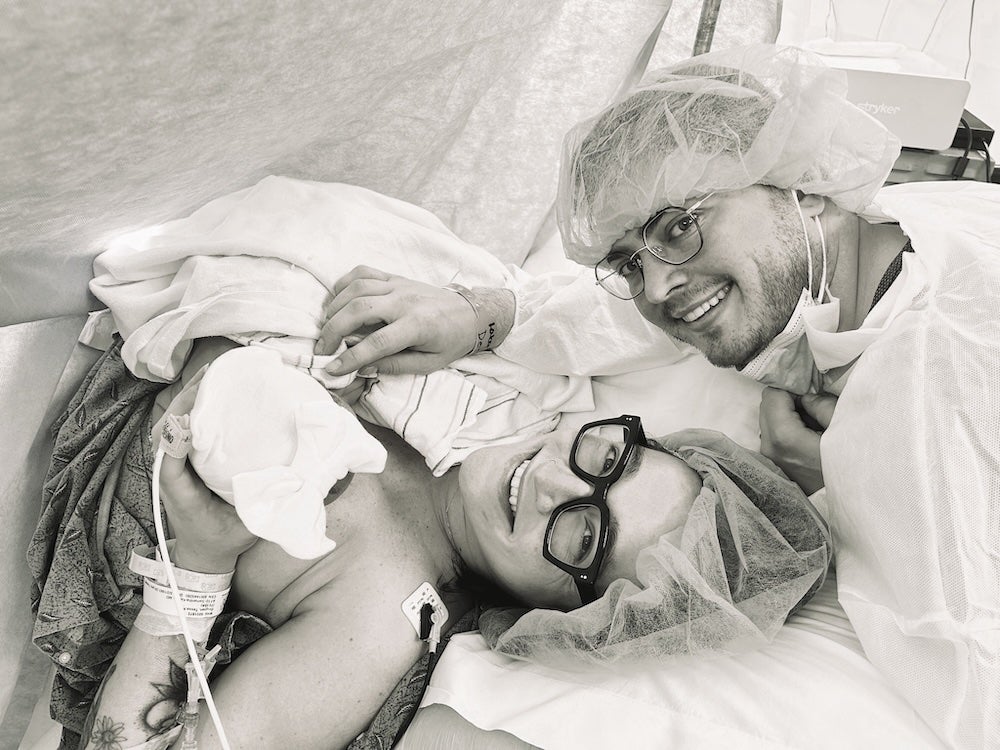 Tessa Deignan, immediately postpartum, with her family Tessa Deignan immediately post C section, holding her new baby, with her spouse (in scrubs) leaning over her. Both adults are smiling