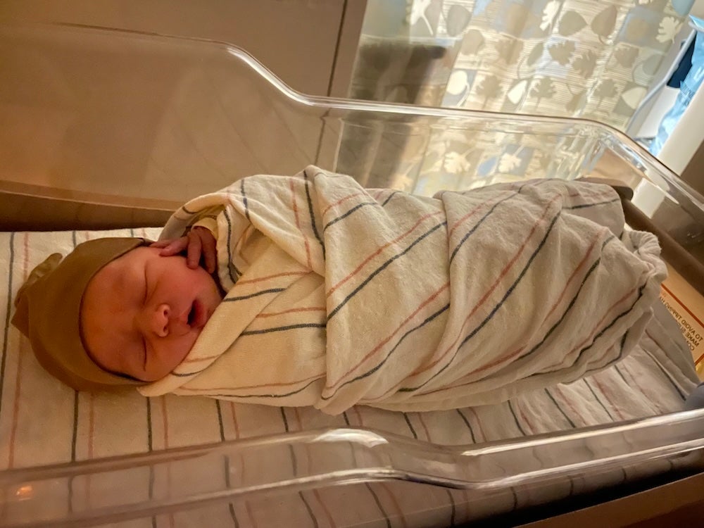 Newborn baby T. relaxes after a day of excitement Newborn baby T., all swaddled up, with tiny fingers splayed across her cheek