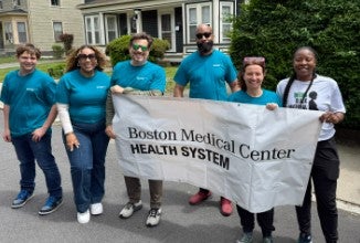 group of people in blue shirts holding bmchs banner