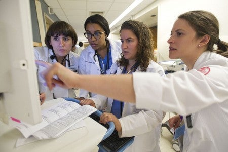 La pasante Juliana Castedo (desde la izquierda), la residente Stephanie Charles, la pasante Julie Bartolomeo (MED'15) y Veronica Torres (MED'16) en el trabajo en Boston Medical Center en julio. Foto de Cydney Scott